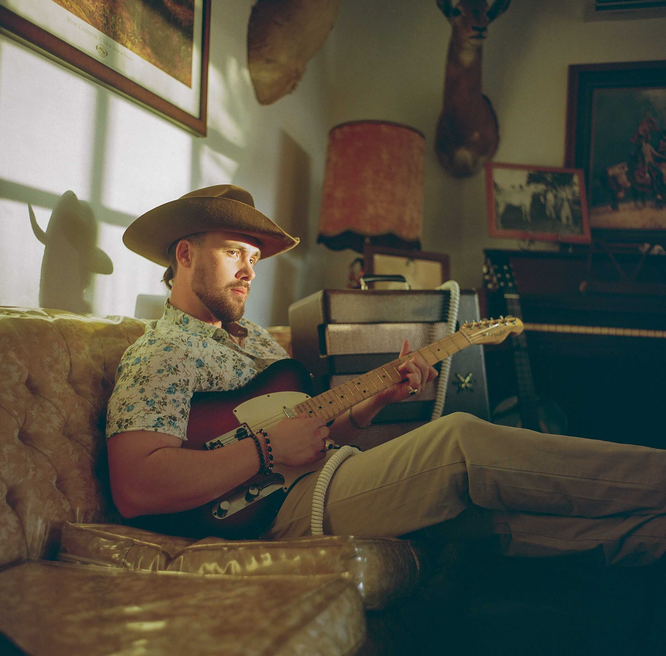 A man playing a guitar while sitting on a couch